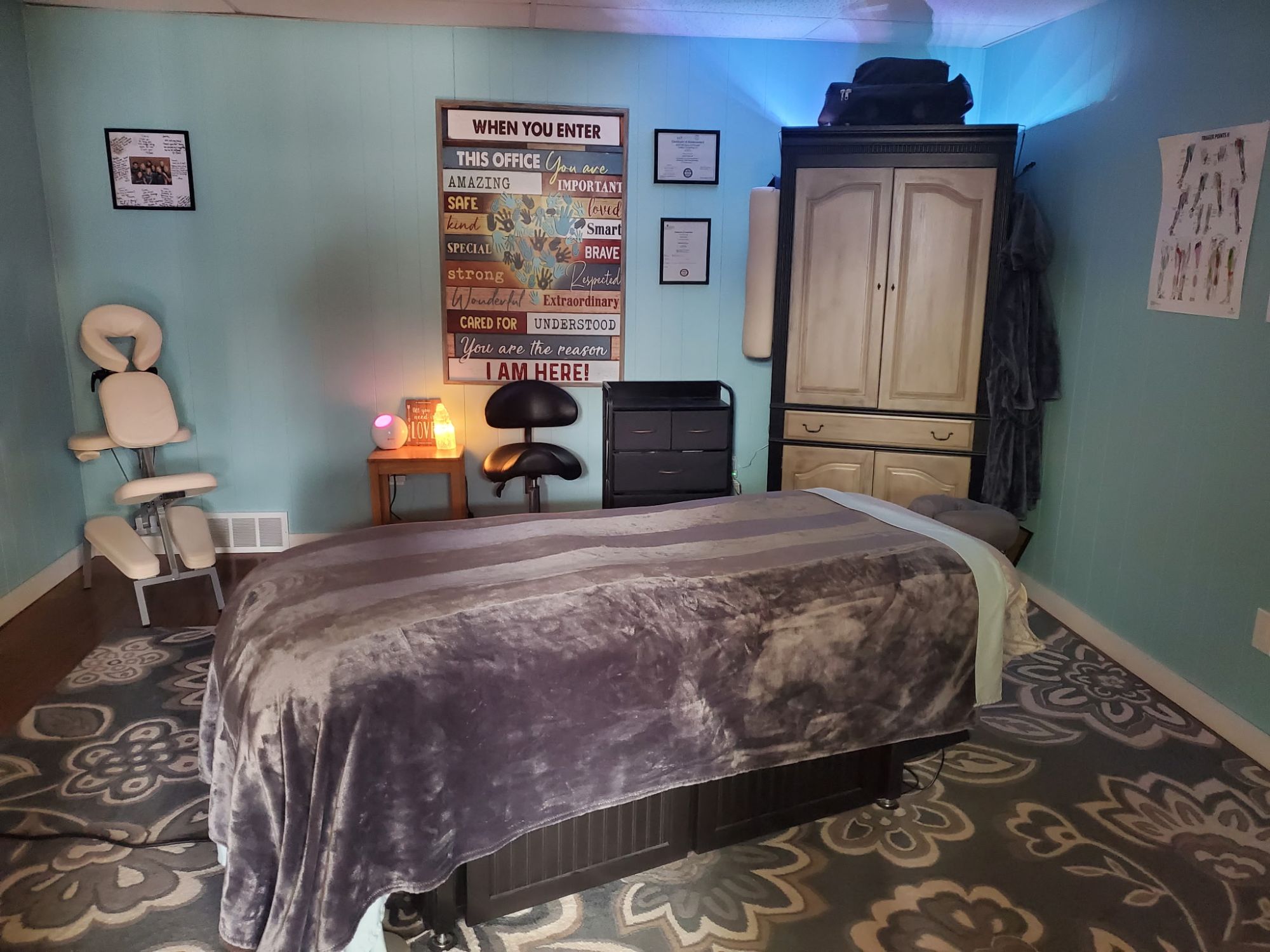 A calming massage treatment room at fhL Massage & Wellness with a draped table, salt lamp, and soft teal walls