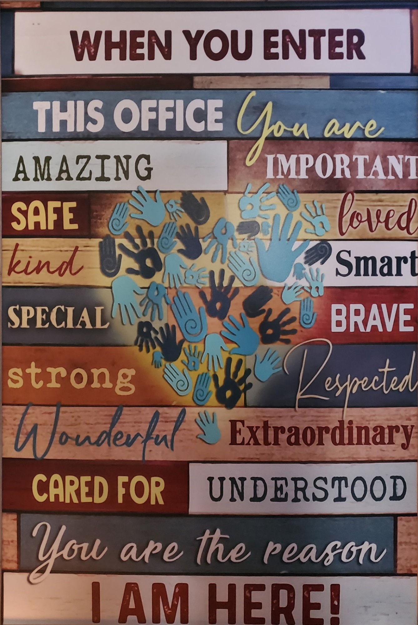 A colorful sign in the office reading 'When you enter this office you are amazing, important, loved, safe, cared for — you are the reason I am here'