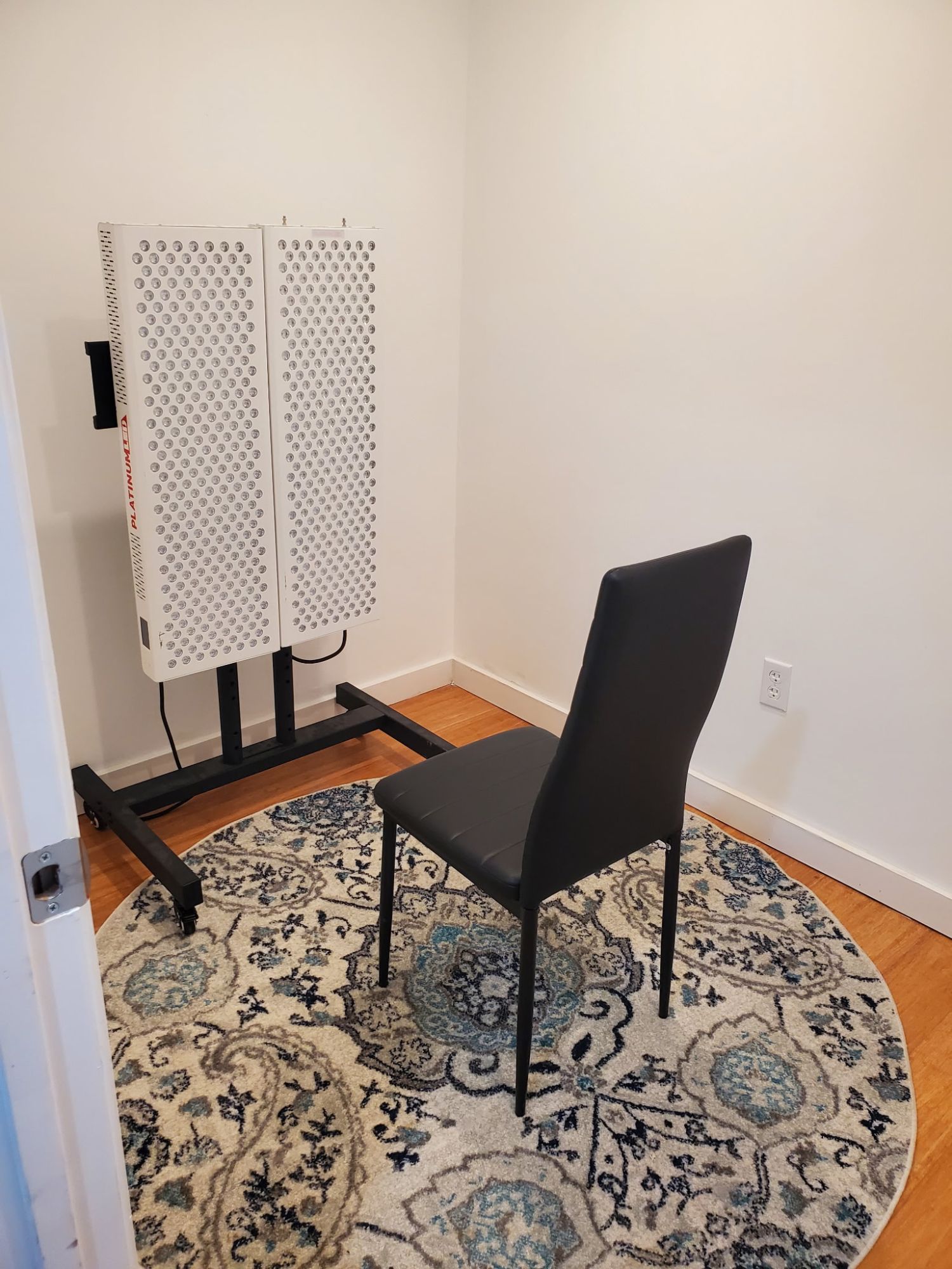 The red light therapy panels at fhL Massage & Wellness, on a rolling stand beside a chair